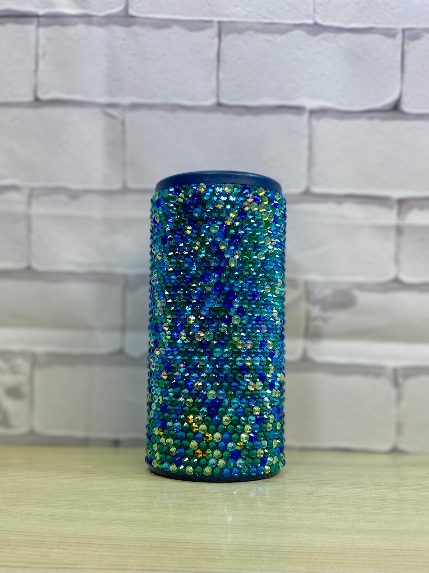 A stainless steel koozie with a rhinestone design, primarily blue in color.