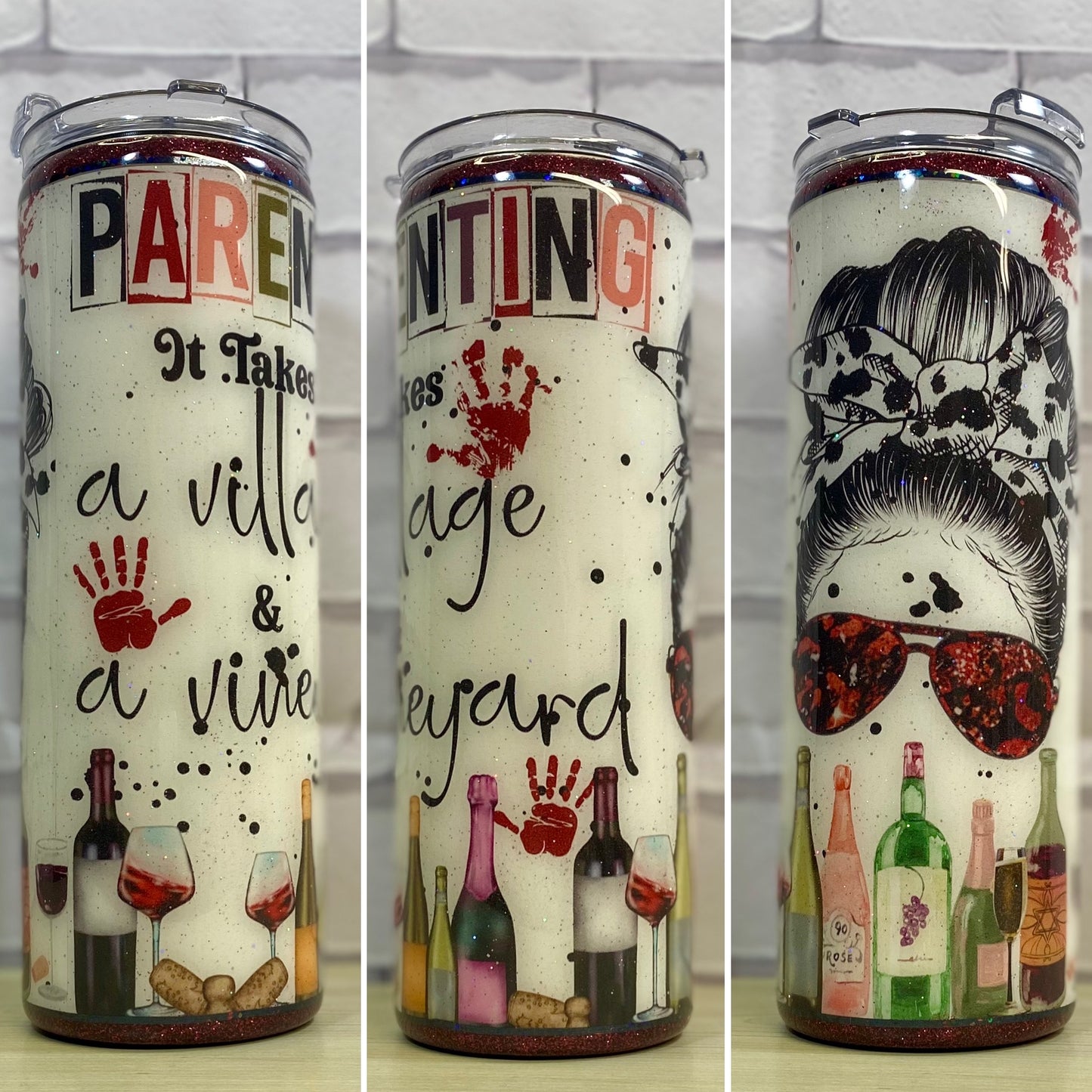 A stainless steel tumbler with a printed design featuring text and graphics related to wine, such as a hand holding a wine glass, and other wine-themed items like grapes and a corkscrew. The tumbler is white with red and black accents.