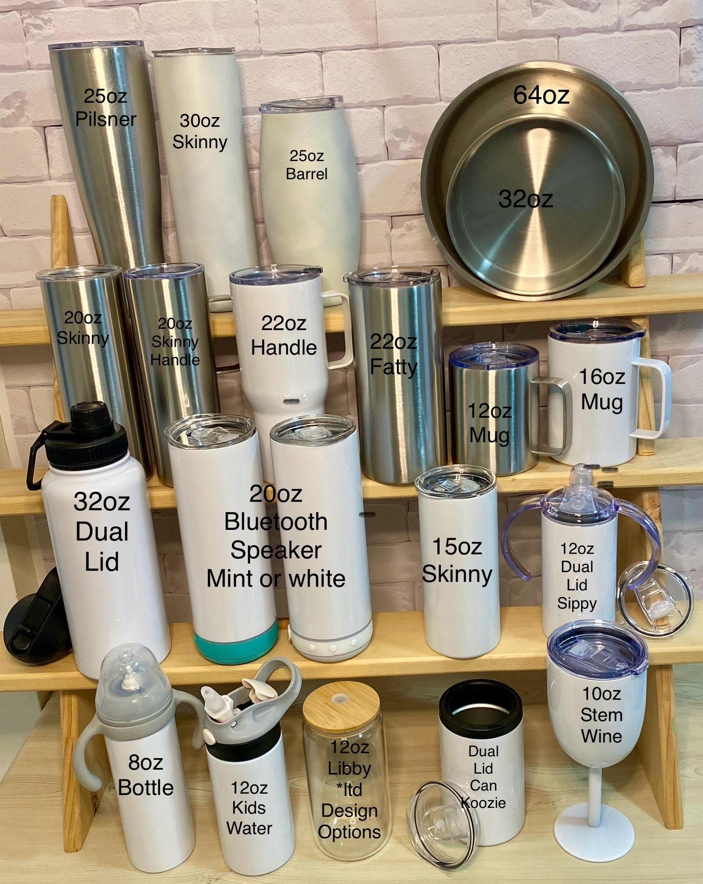 A display of various custom stainless steel tumblers in different sizes and colors, each labeled with their respective sizes and options such as '20oz', '32oz', '40oz', '50oz' and '64oz'. They are arranged on a shelf with a brick wall background.