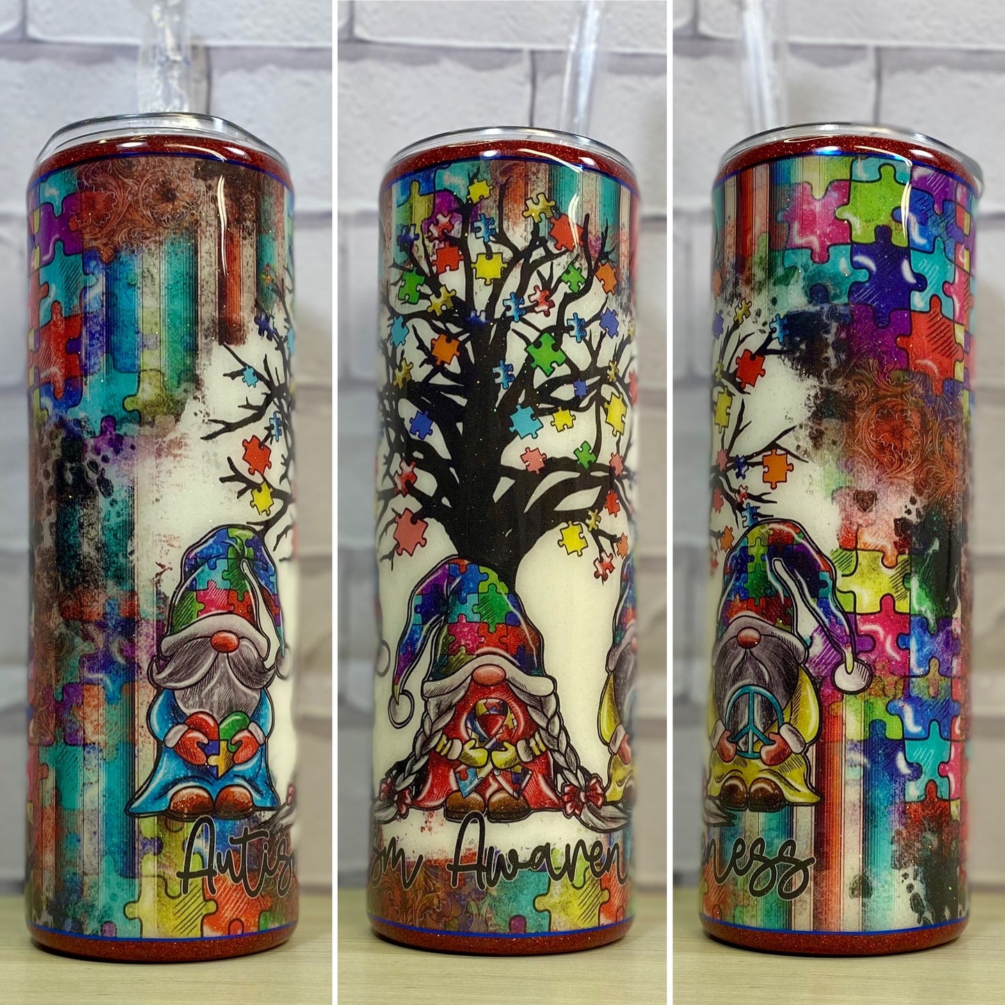 A stainless steel tumbler with a multicolored design featuring puzzle pieces, trees, and a gnome for autism awareness.
