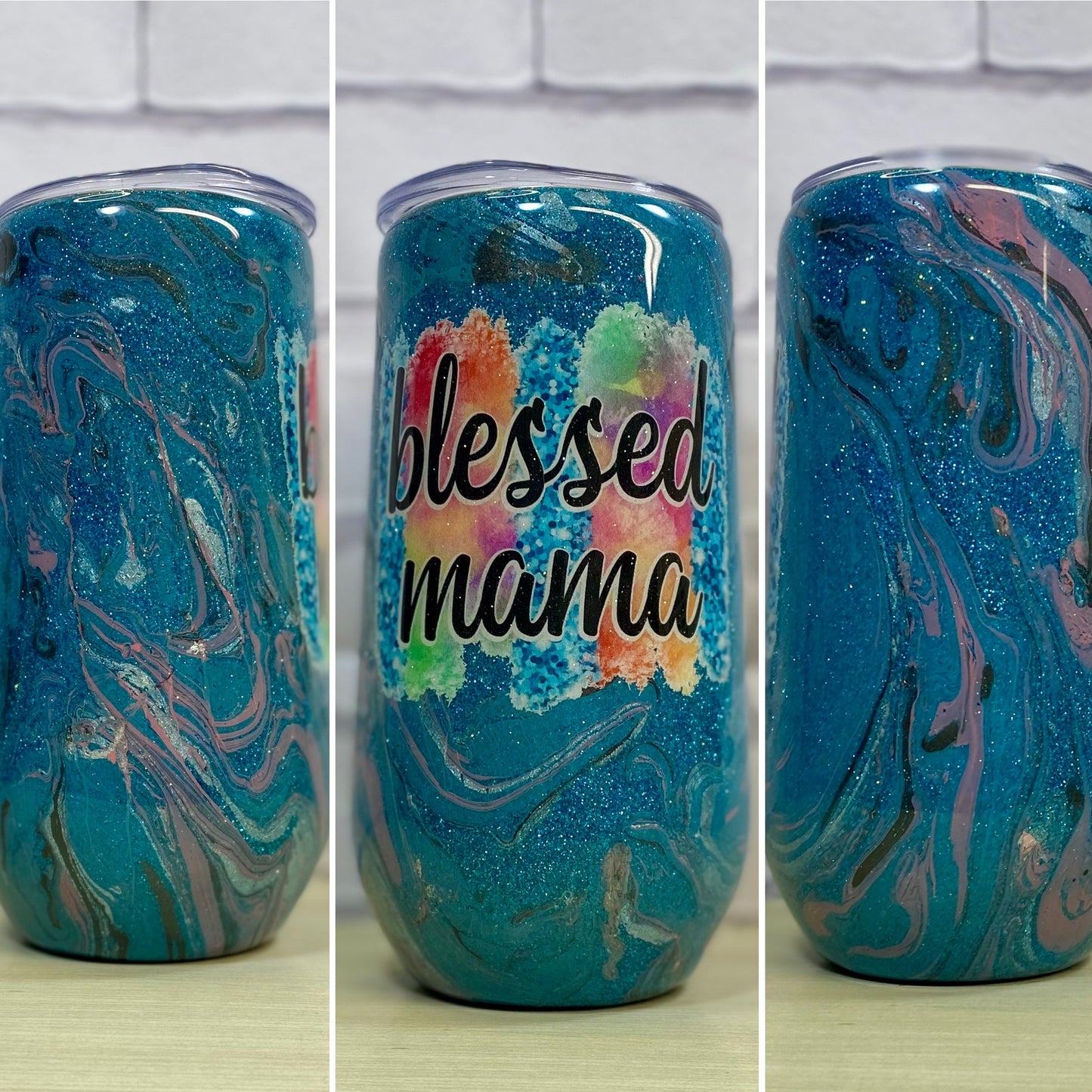 A blue glittered tall wine tumbler with ink swirls that says, blessed mama