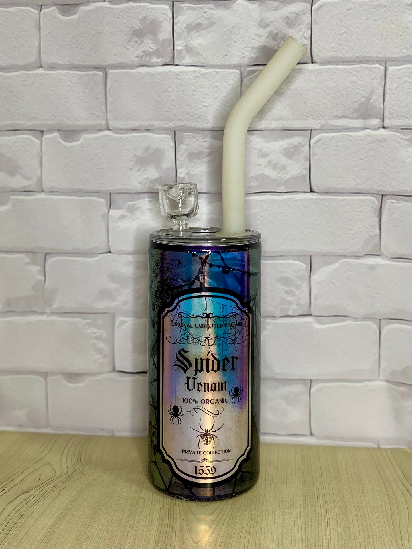 A smoking device with a bowl and a silcone straw made out of a stainess steel tumbler with a spider theme.