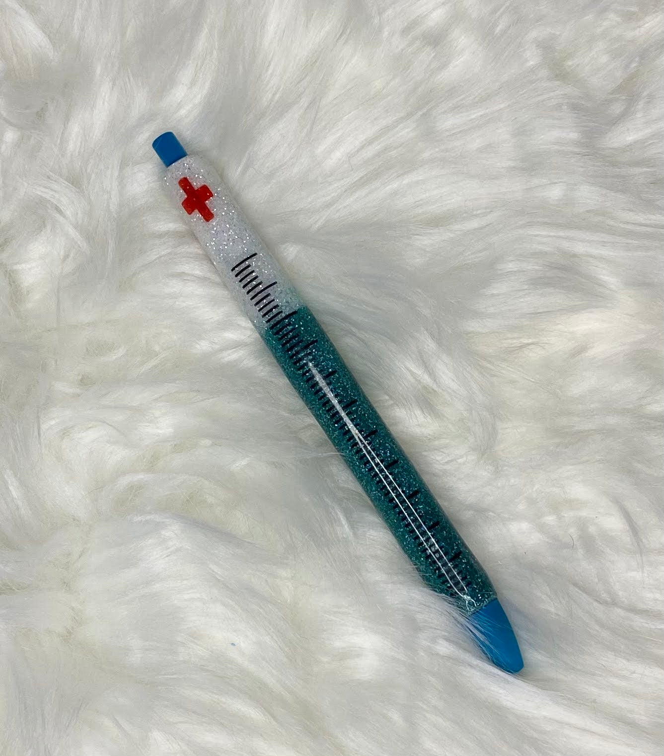 A custom order glitter pen with a blue body, white cap with a red cross.