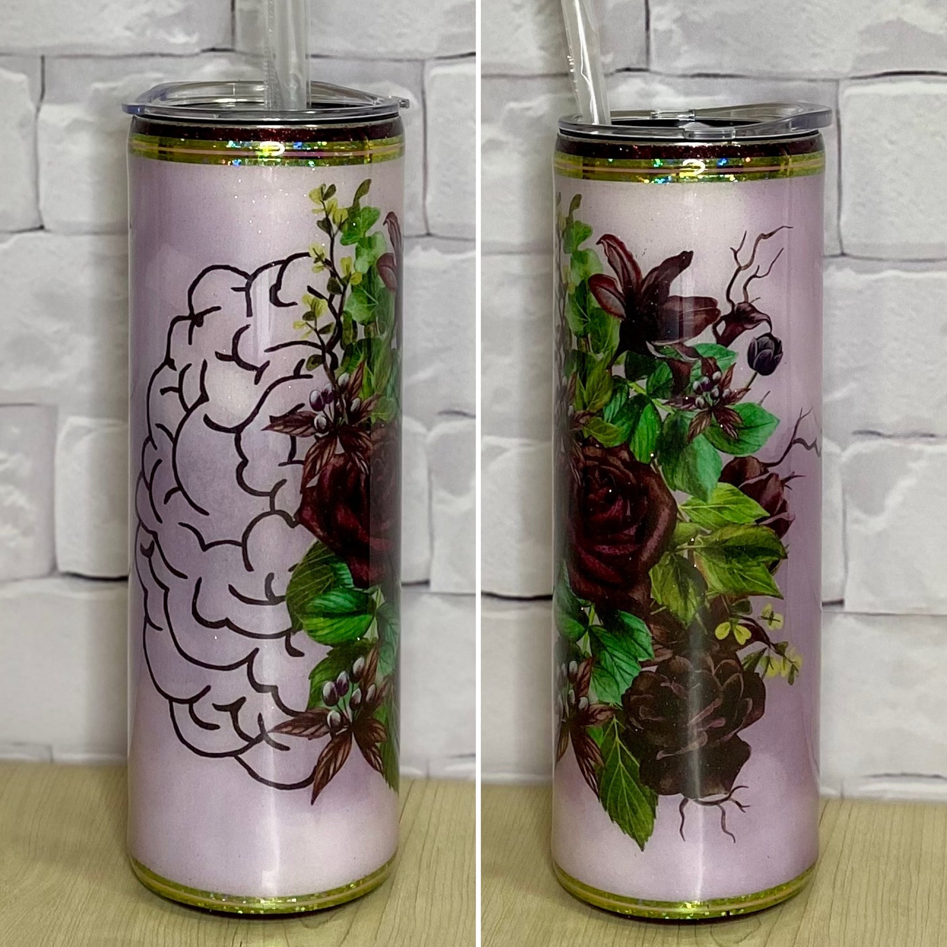 A stainless steel tumbler with a floral and brain design on a white brick background