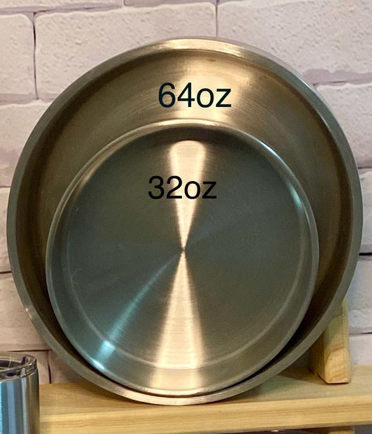 Two stainless steel dog bowls, one marked as 32oz and another as 64oz, placed one inside the other on a wooden surface.